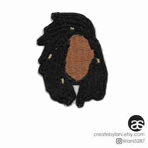 Op de afbeelding: Geborduurde strijk-patch met een zwart silhouet van een persoon met lange dreadlocks en een bruin gezicht. De dreadlocks hebben gouden accenten.