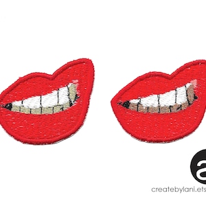 May include: Two red embroidered iron-on patches of a smiling mouth with gold teeth. The patches are approximately 2 inches wide.