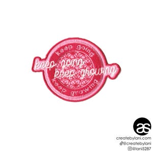 May include: A pink embroidered patch with the words "keep going, keep growing" in white script. The patch has a circular design with a floral pattern in the center and a scalloped edge.