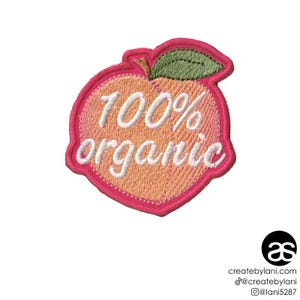 May include: Pink embroidered iron-on patch shaped like a peach with the text "100% organic" in white.