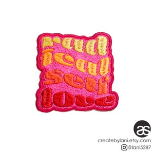 May include: A pink, orange, and yellow embroidered patch with the text "real self love" in a retro font.