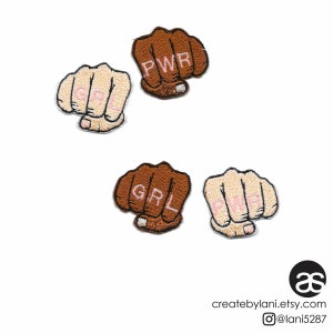 May include: Four embroidered iron-on patches in the shape of a fist with the words "GRL PWR" in pink lettering. The patches are on a white background.