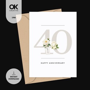 May include: A white anniversary card with the number 40 in light gray, adorned with white roses and a tag that reads "With Love." The words "Happy Anniversary" are printed below. The card is inside a tan envelope.