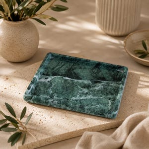 May include: A rectangular tray crafted from dark green marble with prominent white veining throughout. The tray features a smooth, polished surface with slightly raised edges, showcasing the natural stone pattern and deep emerald color tones.