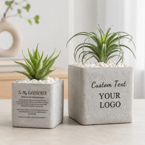 Puede incluir: Dos macetas cuadradas de hormigón gris con guijarros blancos y plantas suculentas verdes. La maceta más pequeña tiene el texto To My GARDENER y un poema. La maceta más grande tiene el texto Custom Text YOUR LOGO en letras negras.