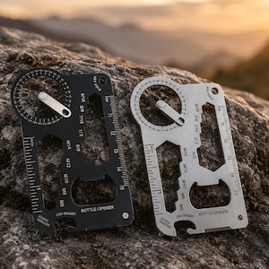 May include: Two multi-tool cards, one black and one silver, are displayed on a rock. Each card includes a ruler, bottle opener, and various wrench sizes. The black card has the text "BOTTLE OPENER" and "CAN OPENER". The silver card has the same features.