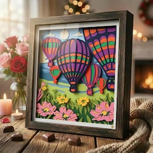May include: A framed paper art piece featuring colorful hot air balloons in a layered design. The balloons are purple, orange, green, and red, set against a blue sky and green landscape with flowers. The frame is a dark brown color.