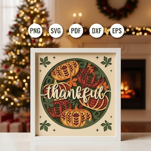 May include: A layered paper art piece in a white frame, featuring a circular design with pumpkins in shades of orange and red, surrounded by green leaves. The word "thankful" is scripted across the center. The image includes file type icons: PNG, SVG, PDF, DXF, and EPS.