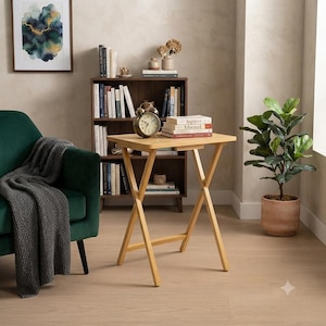 May include: A light-coloured wooden folding table with an X-shaped base. The rectangular tabletop is smooth and flat, supported by four legs that cross in the centre. The table is constructed from light-toned wood with a natural grain finish.