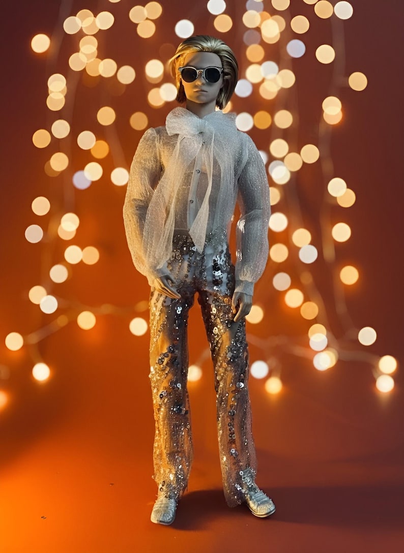 May include: A doll wearing a sheer white blouse with a large bow, sequined pants, and sunglasses. The doll is posed against a warm orange background with blurred string lights. The doll is wearing silver shoes.