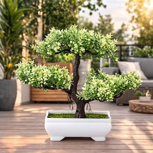 Könnte beinhalten: Ein dekorativer künstlicher Bonsai-Baum mit hellgrünem Laub und einem dunkelbraunen Stamm. Der Bonsai steht in einem weißen rechteckigen Topf mit einer grünen, moosartigen Basis. Der Topf steht auf einer Holzterrasse.