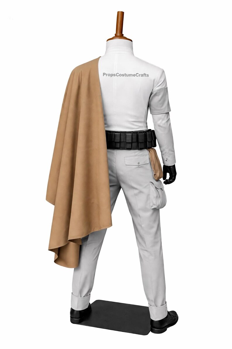 Puede incluir: Un disfraz que consta de una camisa blanca de manga larga, pantalones grises claros, un cintur&oacute;n negro y una capa color canela sobre el hombro. El atuendo incluye guantes y zapatos negros. El texto "PropsCostumeCrafts" es visible en la parte posterior de la camisa.