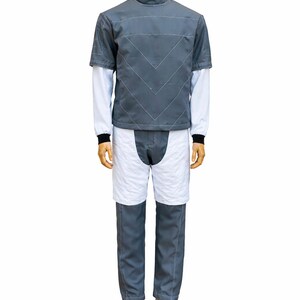 May include: A gray and white outfit displayed on a mannequin. The outfit includes a short-sleeved gray jacket with white stitching, a white long-sleeved undershirt, white shorts, and gray pants. The mannequin is on a wooden base.