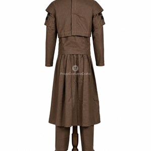 May include: A brown costume displayed on a mannequin. The outfit includes a long-sleeved jacket with shoulder accents, a long skirt, and pants. The costume is made of a solid brown fabric and is paired with black shoes.