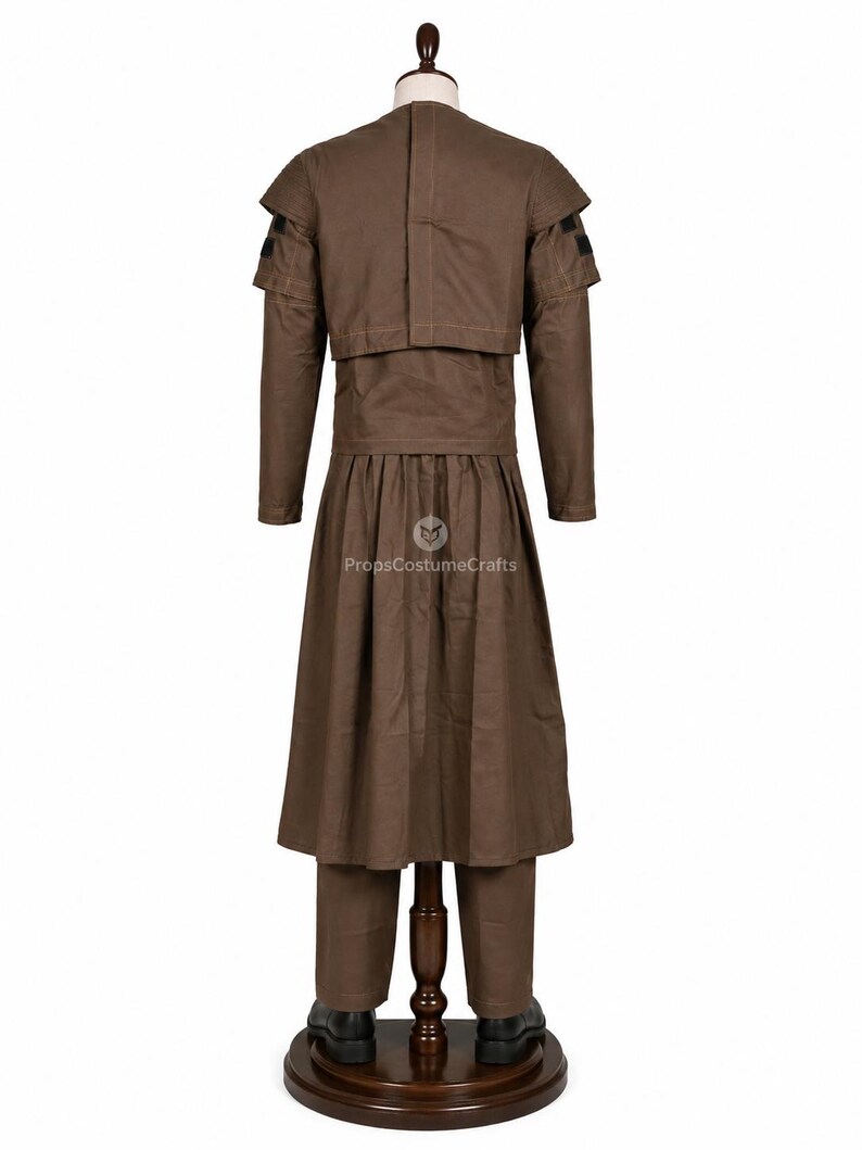 May include: A brown costume displayed on a mannequin. The outfit includes a long-sleeved jacket with shoulder accents, a long skirt, and pants. The costume is made of a solid brown fabric and is paired with black shoes.