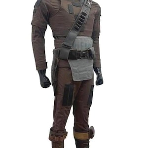 May include: A brown and grey costume with a high collar, shoulder pads, and a utility belt. The costume includes a chest piece, leg armour, and a shoulder strap with pouches. The outfit is displayed on a mannequin.