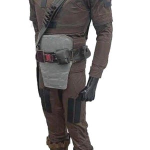 May include: Brown tactical costume featuring a high collar, shoulder strap, and multiple pockets. The outfit includes a belt with pouches, a chest protector, and knee pads. Black gloves complete the look.