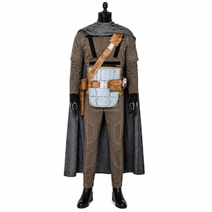 May include: A brown long-sleeved jumpsuit with a textured grey cape, a tan utility belt featuring a light blue rectangular plate, a brown holster, and a small pouch. The outfit includes black gloves and black boots, creating a complete ensemble.