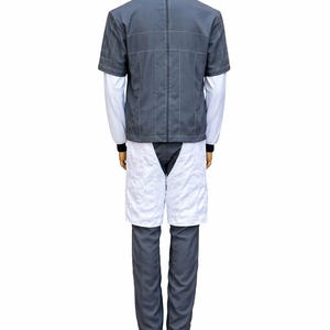May include: A gray and white uniform displayed on a mannequin. The outfit includes a short-sleeved gray jacket with white stitching, a white long-sleeved shirt, gray pants, and white shorts. The mannequin stands on a wooden base.