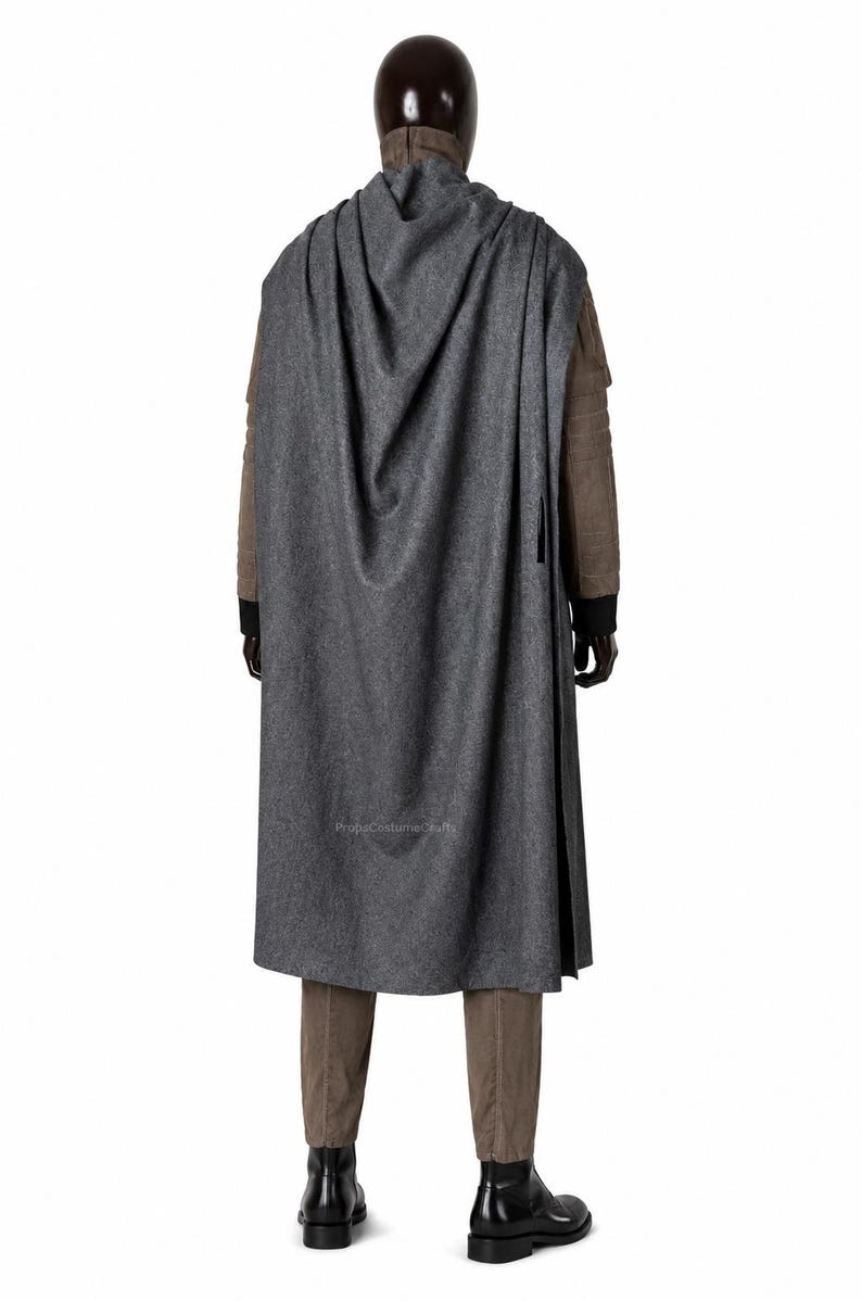May include: A long, dark grey hooded cloak worn over a brown jacket with black cuffs, brown trousers, and black boots. The cloak features a textured fabric and drapes down the back. The text PropsCostumeCrafts is visible on the lower cloak.