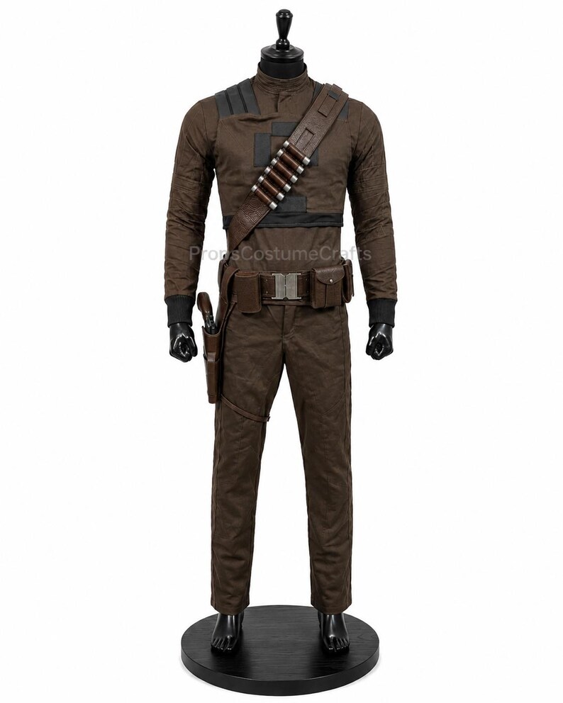 May include: A brown long-sleeved shirt and matching trousers costume set on a mannequin. The outfit includes a dark brown diagonal shoulder strap with silver-toned cylindrical accents, a utility belt with pouches, and a holster for a sidearm.