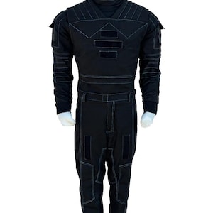 May include: Black jumpsuit with white stitching details. The outfit features a high collar, long sleeves, and multiple rectangular patches on the chest and legs. The jumpsuit is displayed on a mannequin.