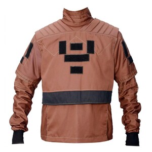 May include: A brown jacket with black accents. The jacket features a high collar, quilted shoulder detailing, and black patches on the back and sleeves. The sleeves have black cuffs. The jacket has a black band across the lower back.