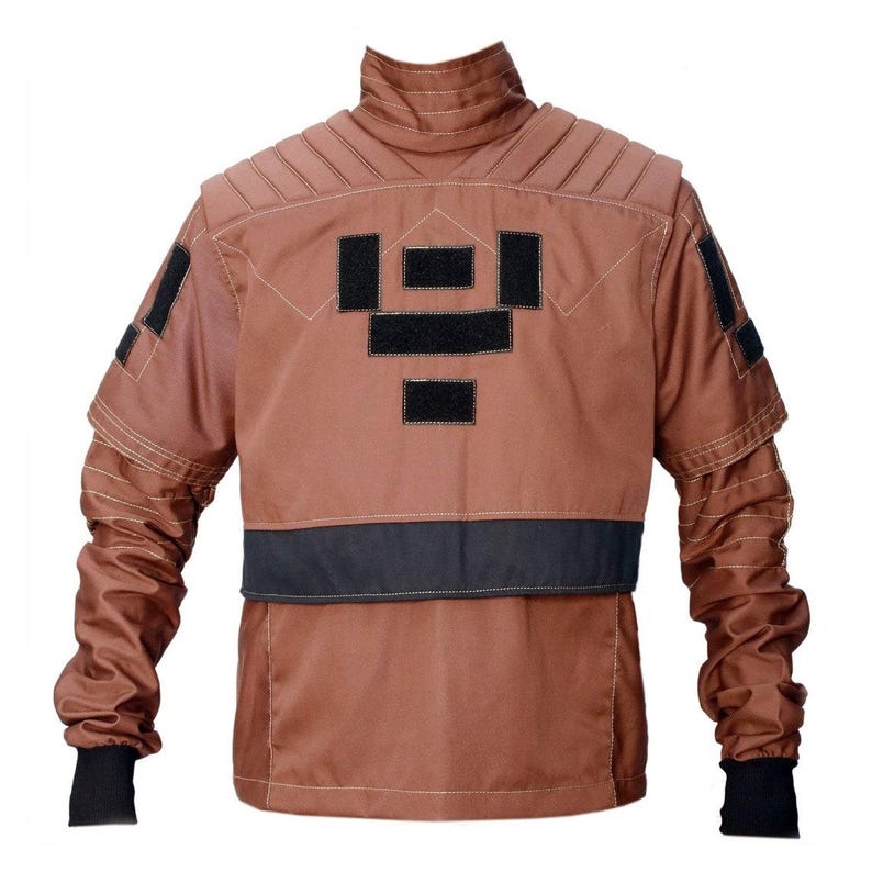 May include: A brown jacket with black accents. The jacket features a high collar, quilted shoulder detailing, and black patches on the back and sleeves. The sleeves have black cuffs. The jacket has a black band across the lower back.