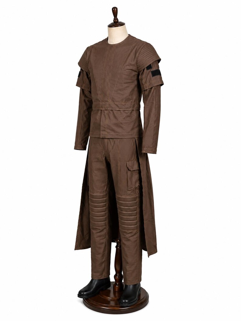 May include: A brown costume displayed on a mannequin. The outfit includes a long-sleeved top with shoulder accents, a matching belt, and pants with knee padding. The costume is completed with a long coat and black boots.