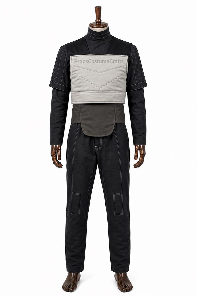 May include: A black long-sleeved shirt and matching trousers set featuring white contrast stitching. A light gray quilted chest panel with the text PropsCostumeCrafts is layered over the shirt, accompanied by a dark gray waist belt component.