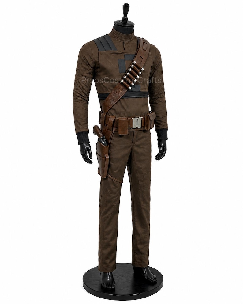 May include: A brown long-sleeved shirt and matching trousers costume set featuring black shoulder and chest accents. The outfit includes a brown leather-look bandolier with silver-toned cartridges, a utility belt with a holster, and a prop pistol.