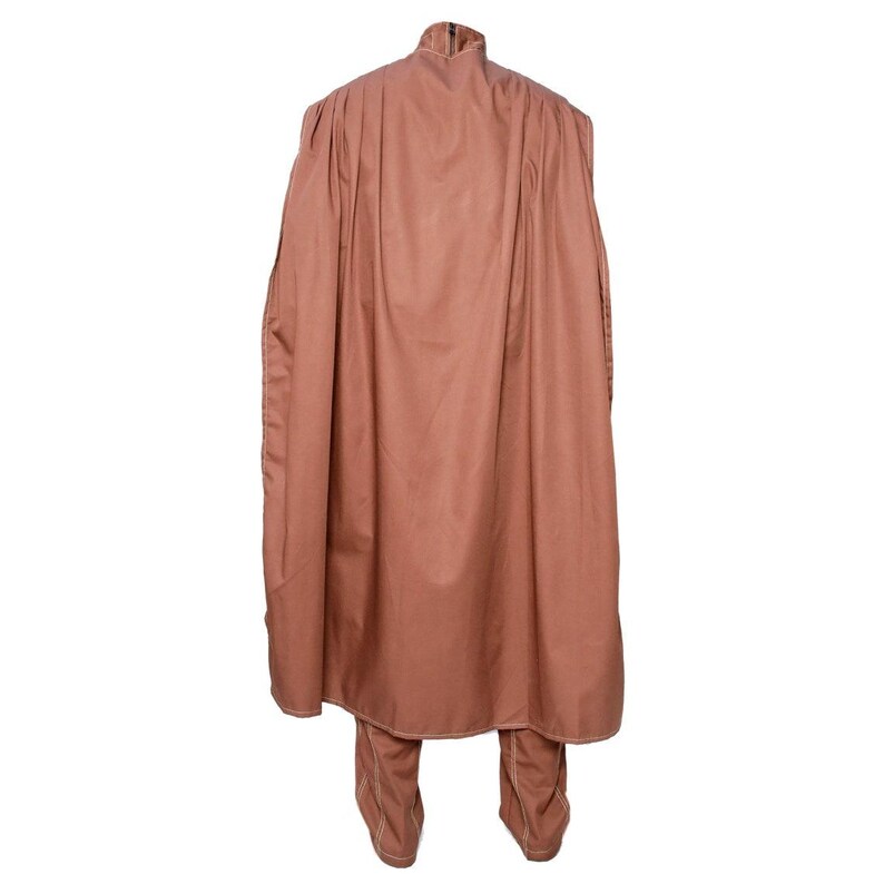 May include: A brown two-piece outfit featuring a high-collared top with a cape-like design and matching pants. The outfit is made of a solid-colored fabric and has a tailored fit. The back view showcases the full silhouette of the garment.