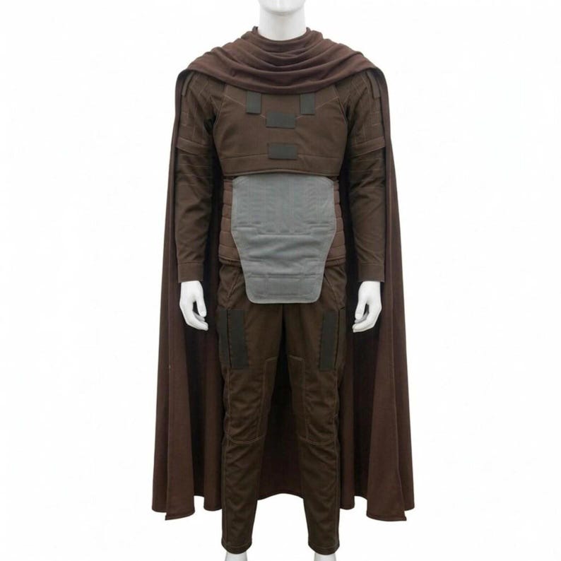 May include: A brown costume with a matching cape. The outfit includes a long-sleeved top, pants, and a chest piece. The cape drapes over the shoulders. The costume is displayed on a mannequin.