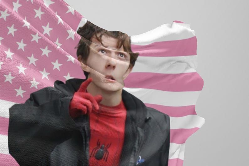 Puede incluir: Una persona con una camiseta roja y negra de Spider-Man y una chaqueta negra, con guantes rojos, se&ntilde;alando. Una bandera rosa y blanca est&aacute; en el fondo.