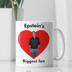 May include: White ceramic mug featuring a red heart graphic and the text "Epstein's Biggest fan." The heart contains a photo of a man in a navy blue shirt and jeans. The mug has a white handle.