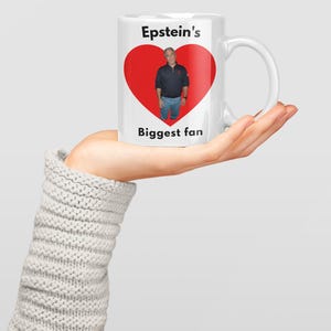May include: White ceramic mug with a handle, featuring a red heart design with a photo of a man inside. The text "Epstein's Biggest fan" is printed on the mug.