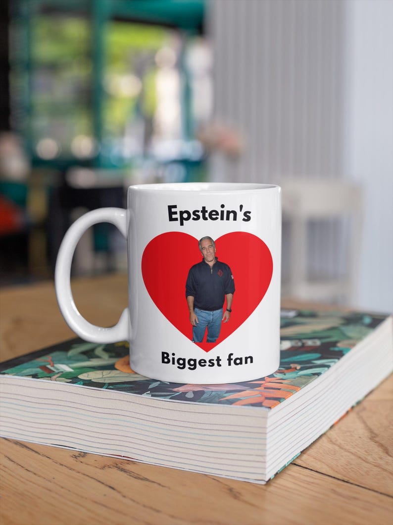 May include: White ceramic mug with a red heart design. The mug has a photo of a man inside the heart, with the text "Epstein's Biggest fan" printed above and below the heart.