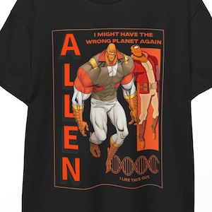 Könnte beinhalten: Schwarzes T-Shirt mit einer Comic-Illustration einer muskulösen Figur. Das Design enthält das Wort "ALLEN" vertikal sowie die Sätze "I MIGHT HAVE THE WRONG PLANET AGAIN" und "I LIKE THIS GUY".