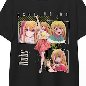 May include: Black t-shirt featuring a colorful anime graphic. The design includes the text "OSHI NO KO" and the name "Ruby" in a vertical font. The graphic showcases a character in various poses with blonde hair and a pink skirt.