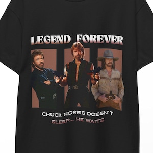 Può includere: T-shirt nera con una grafica di Chuck Norris in tre pose diverse, con la scritta "LEGEND FOREVER" sopra le immagini. Sotto le immagini, la scritta recita "CHUCK NORRIS DOESN'T SLEEP... HE WAITS."