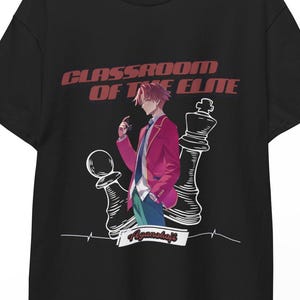 Può includere: T-shirt nero con grafica di un personaggio anime con giacca rossa, camicia bianca e pantaloni blu, con un pezzo degli scacchi e la scritta "CLASSROOM OF THE ELITE". La maglietta è appesa a una gruccia di legno.