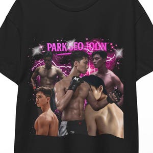 May include: Black t-shirt featuring a graphic of several men in a fighting pose, with the text "PARK SEO JOON" in pink. The design includes a pink lightning bolt effect and star accents.