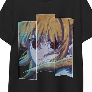 Może przedstawiać: Czarny t-shirt z kolorową ilustracją w stylu anime przedstawiającą twarz postaci. Grafika podzielona jest na trzy pionowe panele, podkreślające oczy i włosy postaci. Projekt nadrukowany jest na klasycznym t-shircie z okrągłym dekoltem.