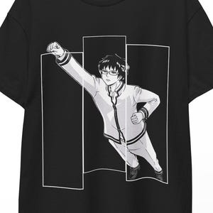 Puede incluir: Camiseta negra con una ilustración de estilo manga de una persona con chaqueta blanca y gafas, con el puño en alto. El gráfico está sobre tres rectángulos blancos verticales.