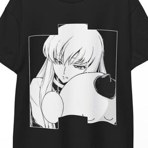 May include: Black t-shirt featuring a black and white anime graphic. The graphic depicts a female character with long white hair and a pensive expression. The design is framed within a white rectangular border.
