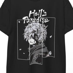 Puede incluir: Camiseta negra con una ilustración en escala de grises de estilo anime de un personaje con cabello desordenado y una bufanda. El texto "Hell's Paradise" está encima del personaje en una fuente estilizada.