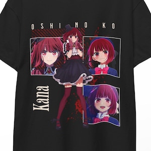 May include: Black t-shirt featuring a graphic of an anime character with red hair and the text "OSHINO KO" and "Kana". The design includes multiple images of the character in different poses. The shirt is hanging on a wooden hanger.