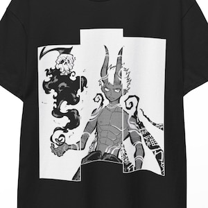 May include: Black t-shirt with a manga-style illustration of a horned demon and a swirling black cloud. The graphic is in black and white, with the demon in the centre of the design. The t-shirt is hanging on a wooden hanger.