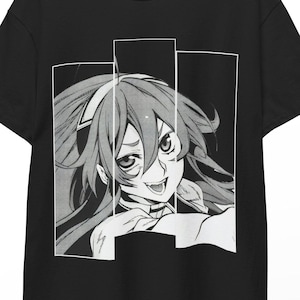 May include: Black t-shirt featuring a manga-style illustration of a character with long hair and a smiling expression. The graphic is framed by white rectangles. The shirt is hanging on a wooden hanger.