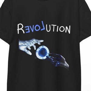 May include: Black t-shirt with the word "REVOLUTION" in white and blue. The graphic depicts two hands interacting with a blue and white circular object. The shirt is hanging on a wooden hanger.